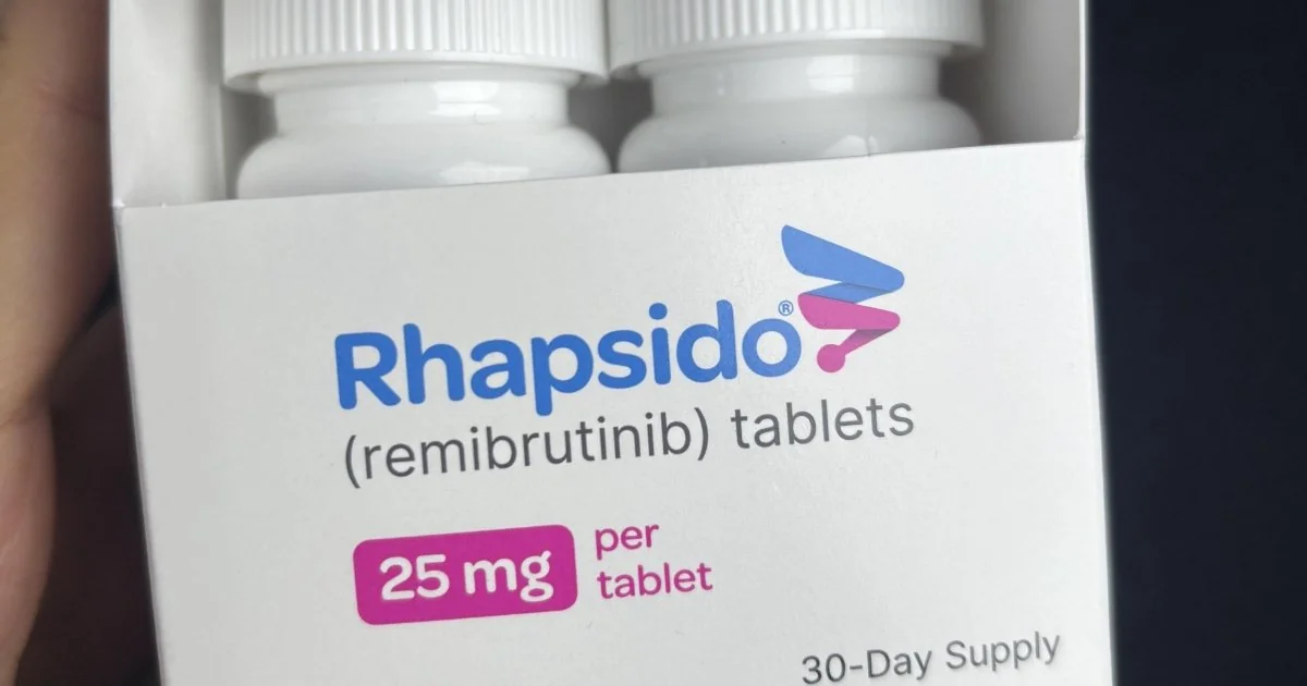 Коробка Rhapsido з двома флаконами таблеток ремібрутинібу 25 мг у руці