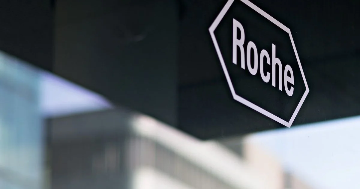 Крупний план білого шестикутного логотипу Roche на темній вивісці будівлі